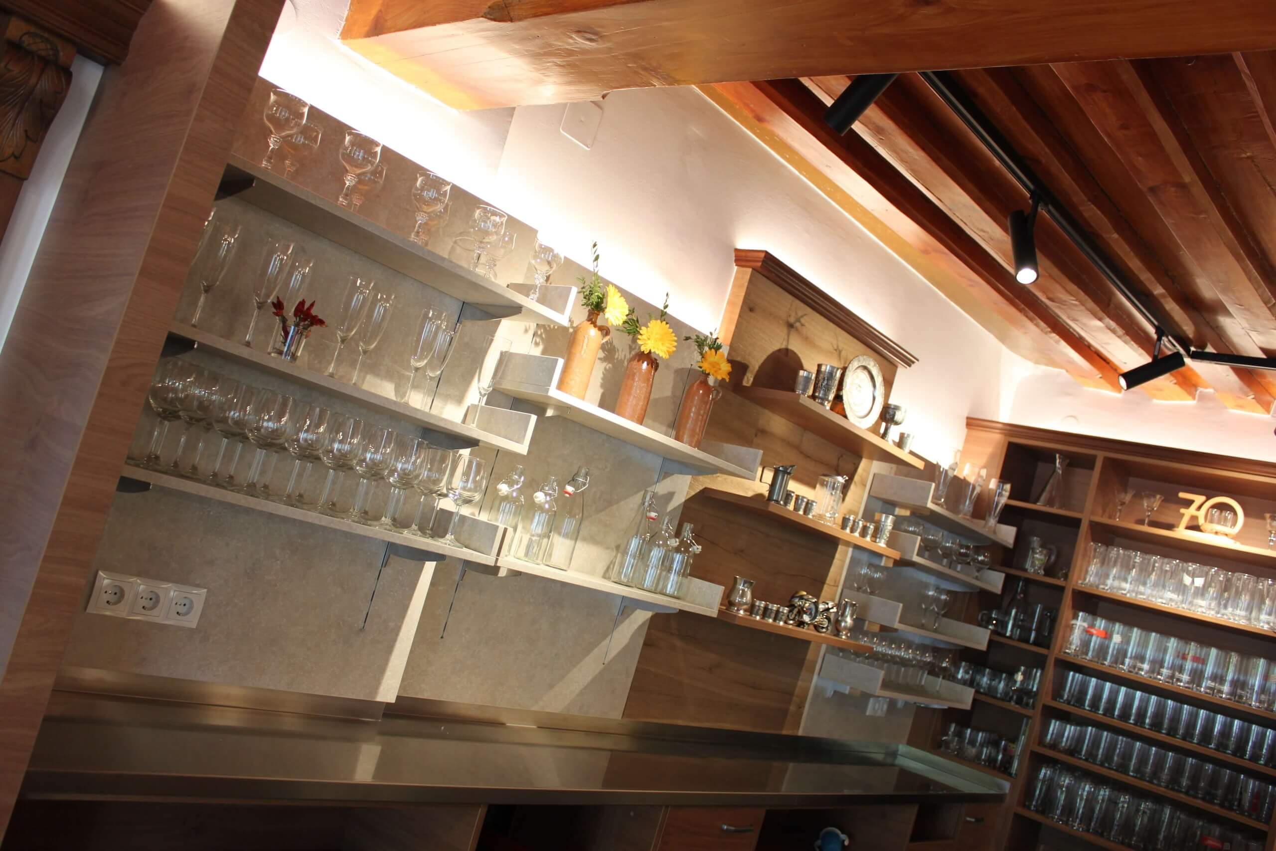 Holzregale in einer stilvollen Bar, gefüllt mit Gläsern und Flaschen für ein elegantes Ambiente.
