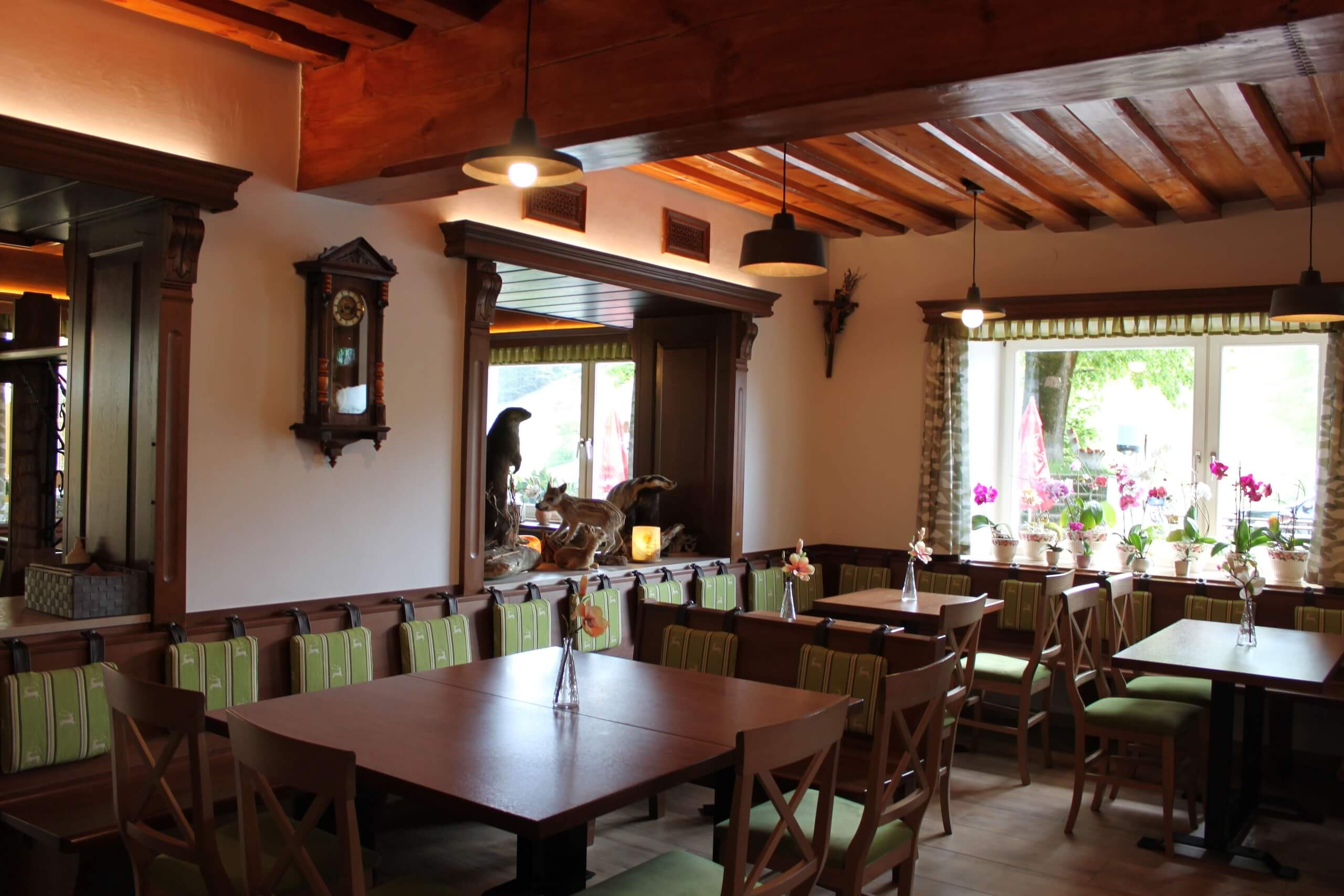 Gemütliches Gasthaus mit Holzmöbeln, Zimmerpflanzen und Wanduhren, ideal für gesellige Treffen und Entspannung.