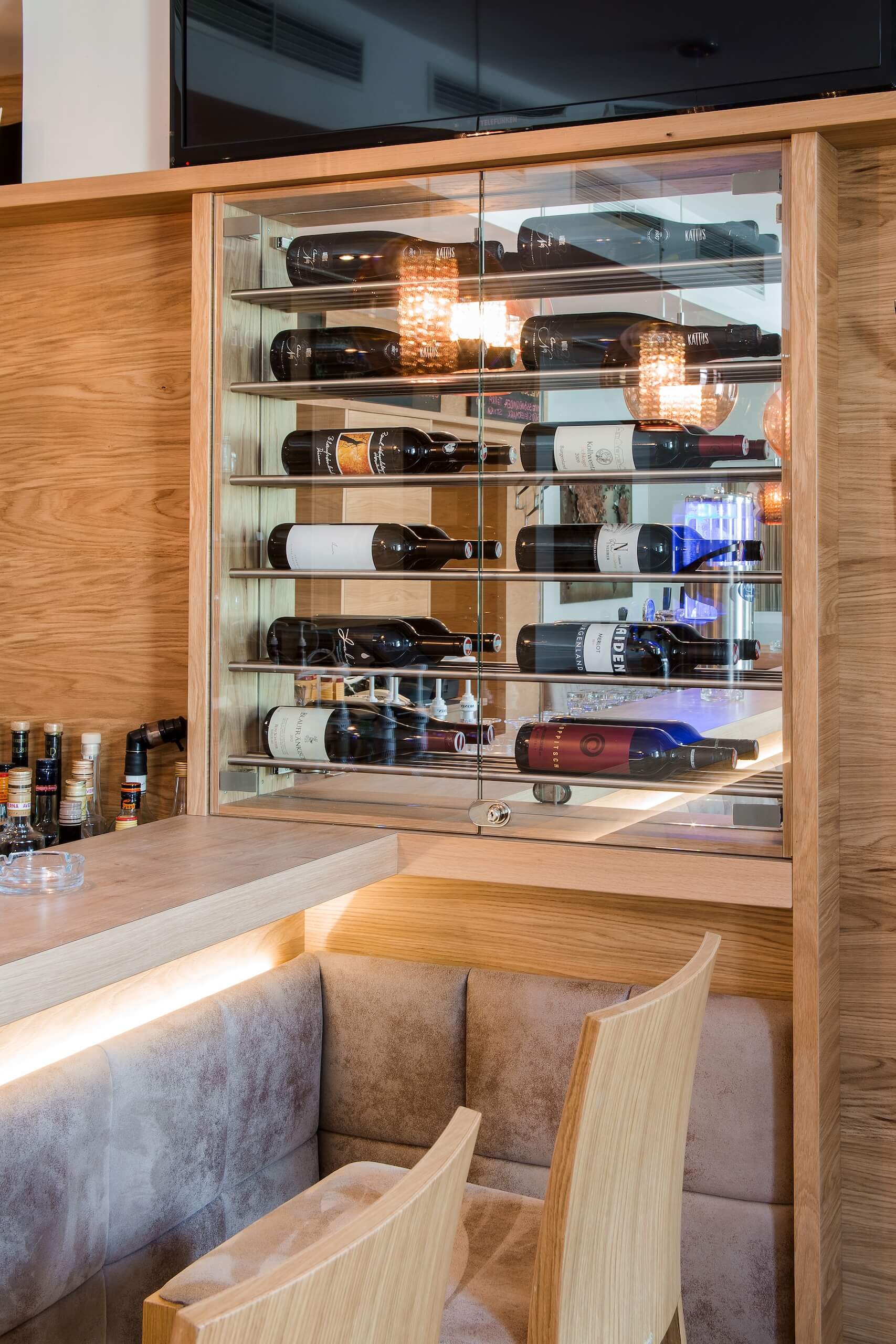 Weinschrank im Restaurant mit eleganter Holzeinrichtung und Vitrinen, gefüllt mit hochwertigen Weinflaschen.