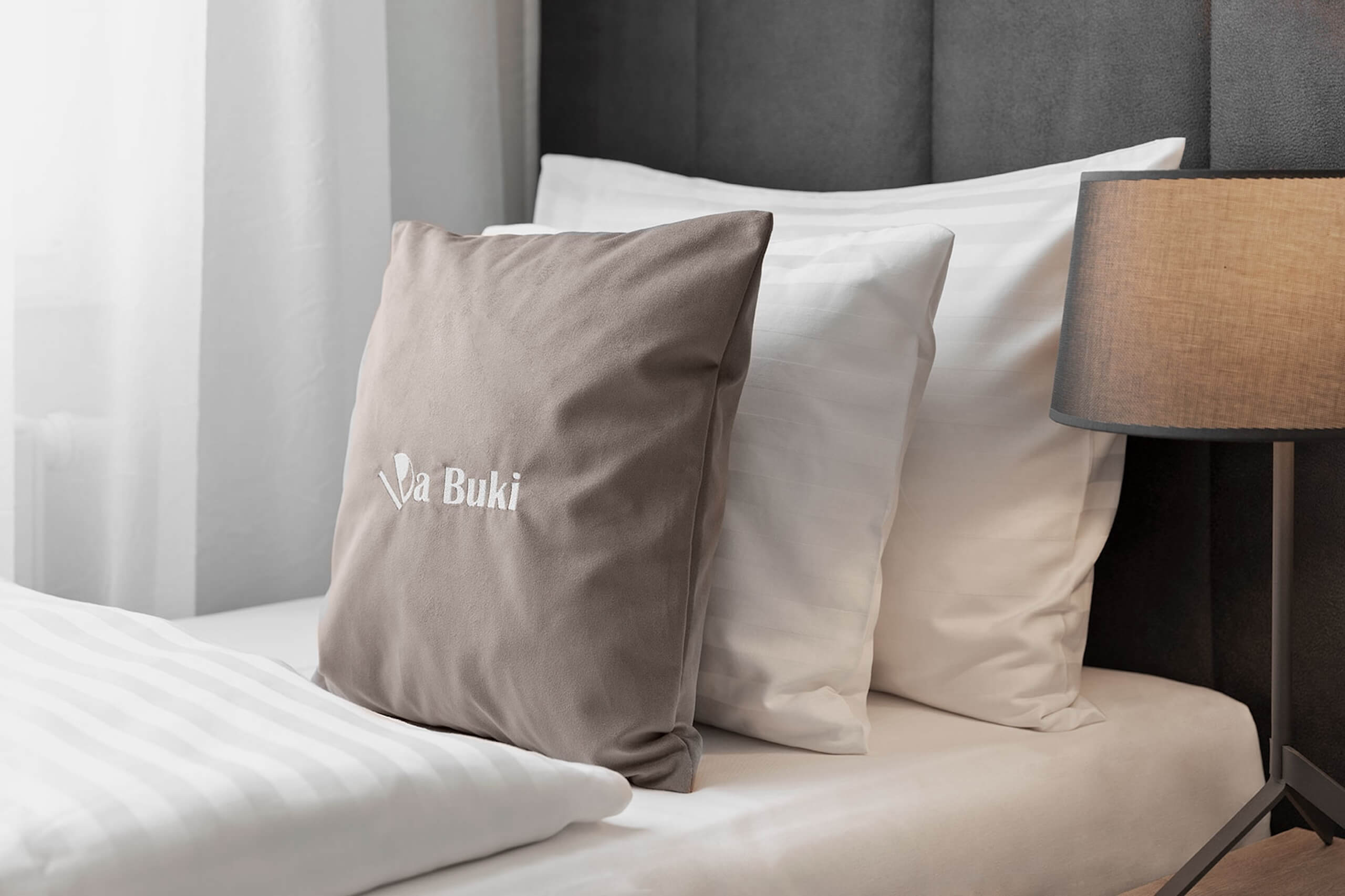 Bett mit Kissen und Lampe, modernes Ambiente, gemütlich und einladend für erholsamen Schlaf.