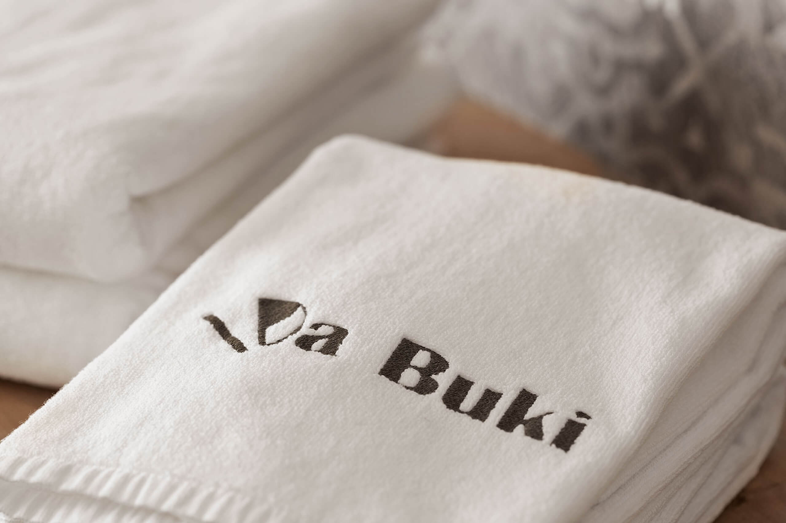 Luxuriöses weißes Handtuch mit gesticktem Logo, perfekt für erstklassige Badezimmer und Spa-Erlebnisse.