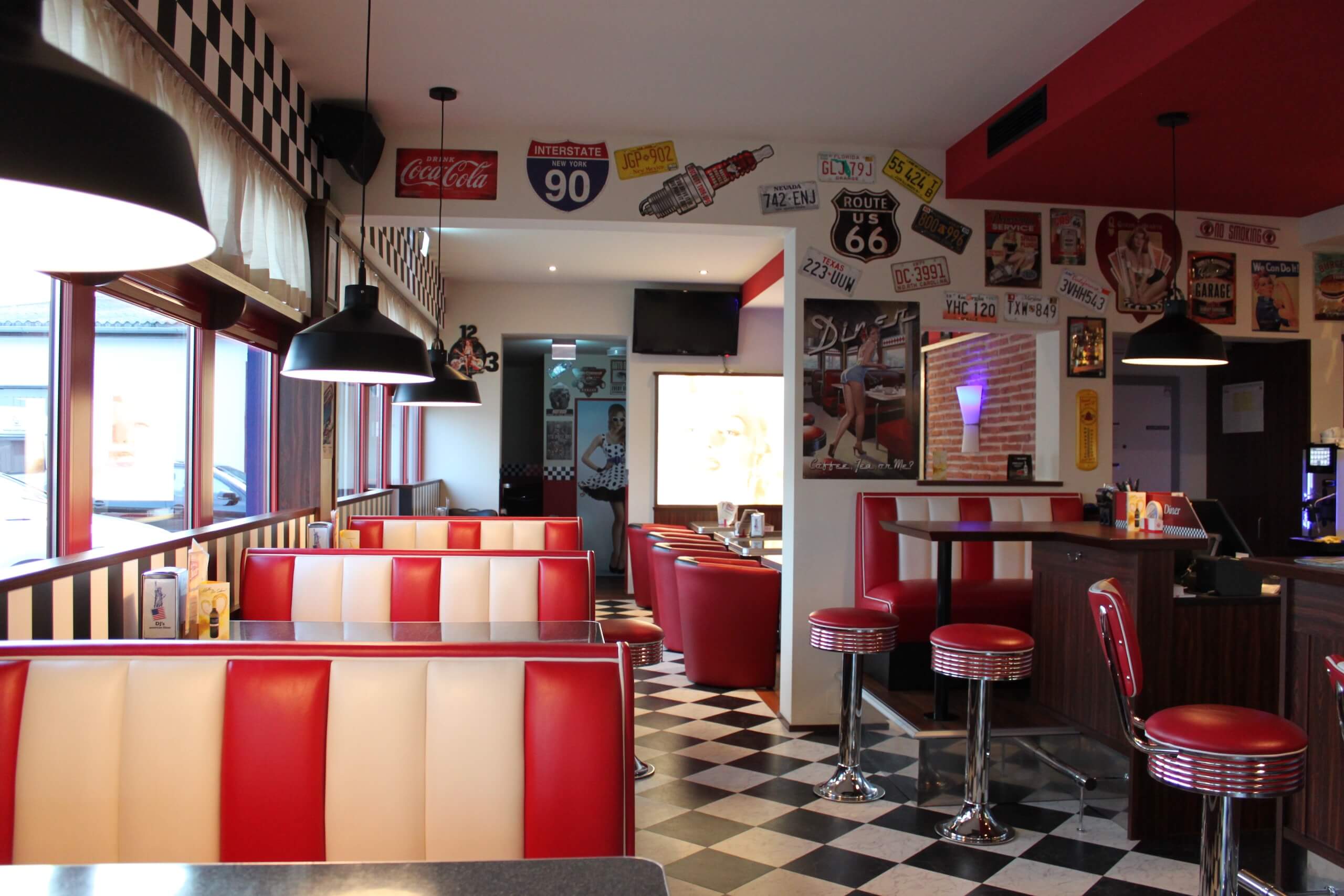 Amerikanisches Diner im Stil der 50er Jahre mit rot-weißen Sitzen und Retro-Dekor, Route 66 Schilder.