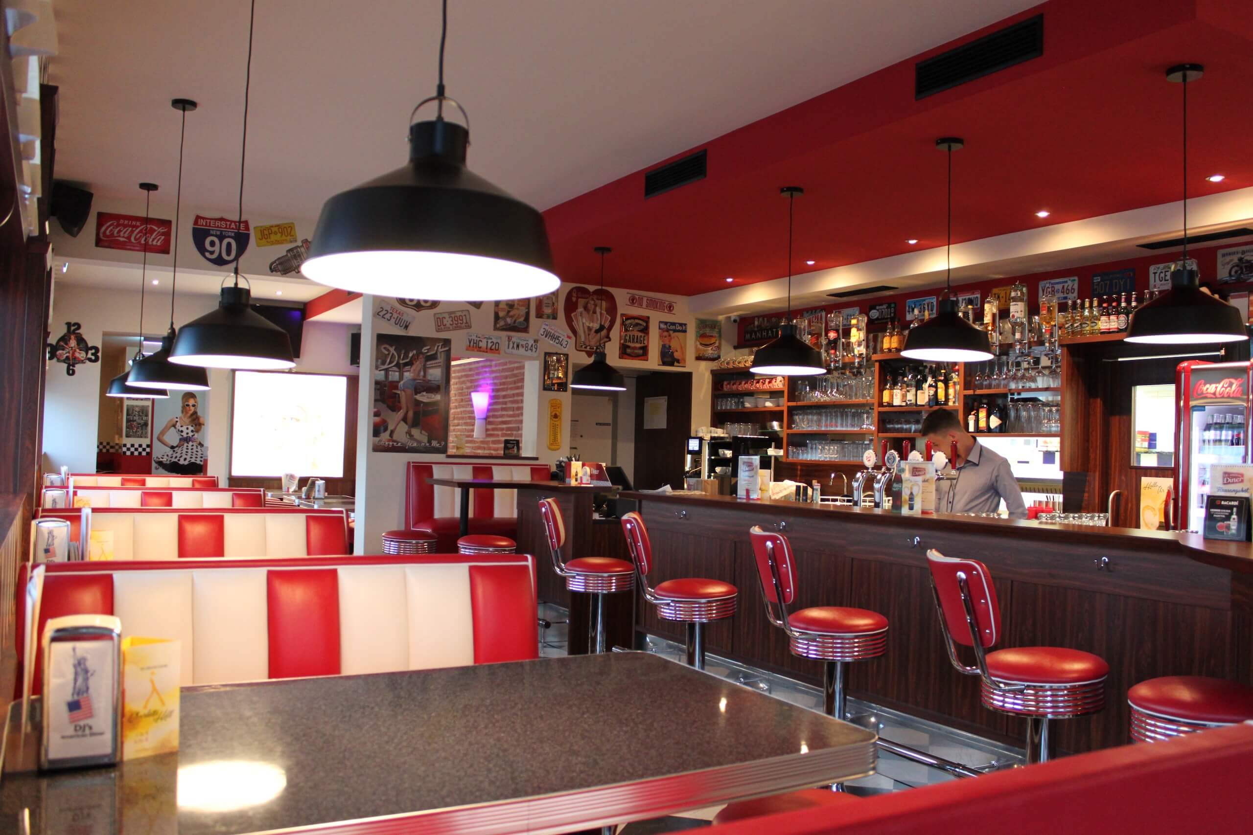 Retro-Diner mit rot-weißen Sitzen, nostalgischen Deko-Elementen und einladender Theke für authentisches Amerika-Feeling.