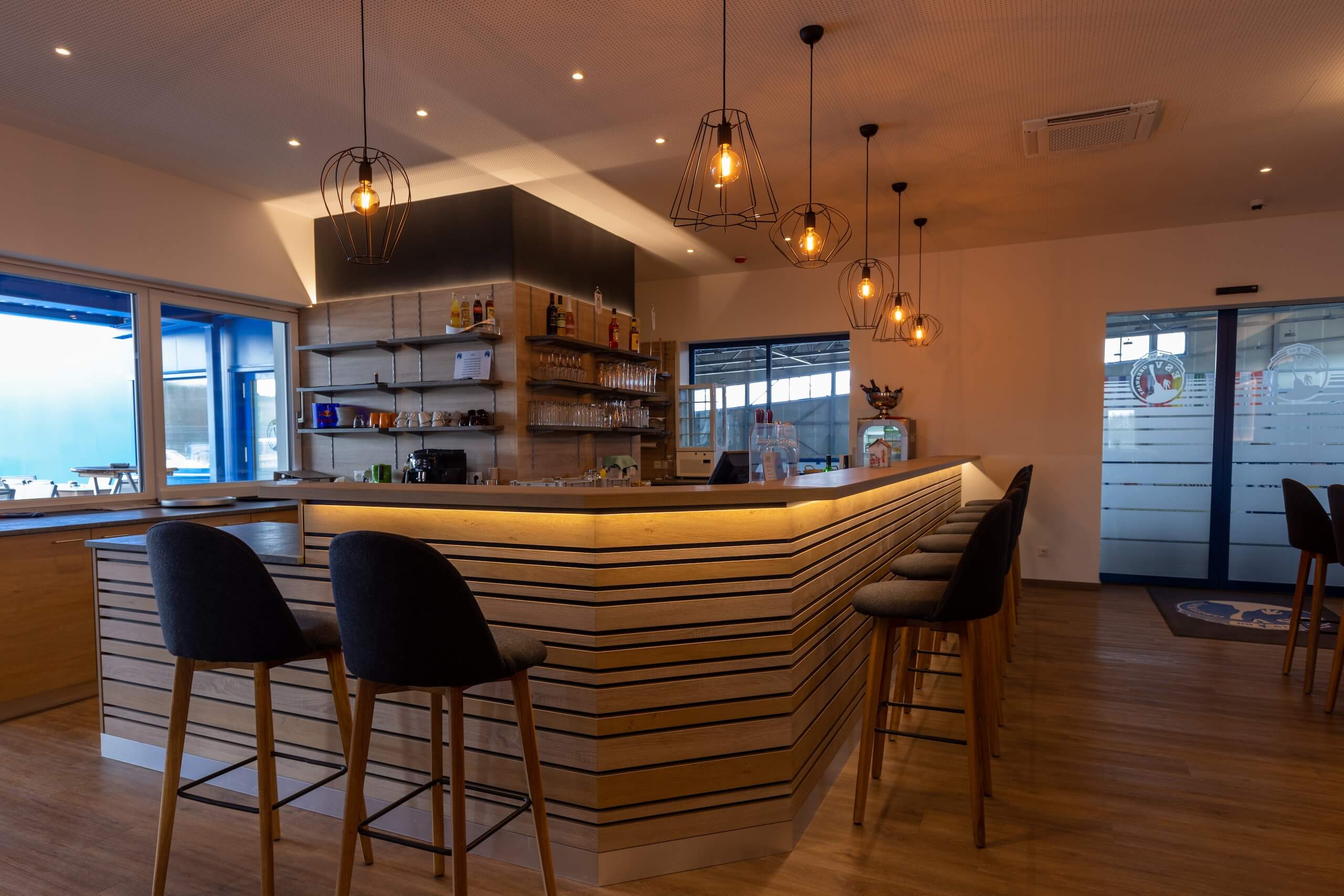 Moderne Bar mit stilvoller Beleuchtung, hohen Stühlen und gemütlichem Ambiente für entspannte Treffen und Drinks.