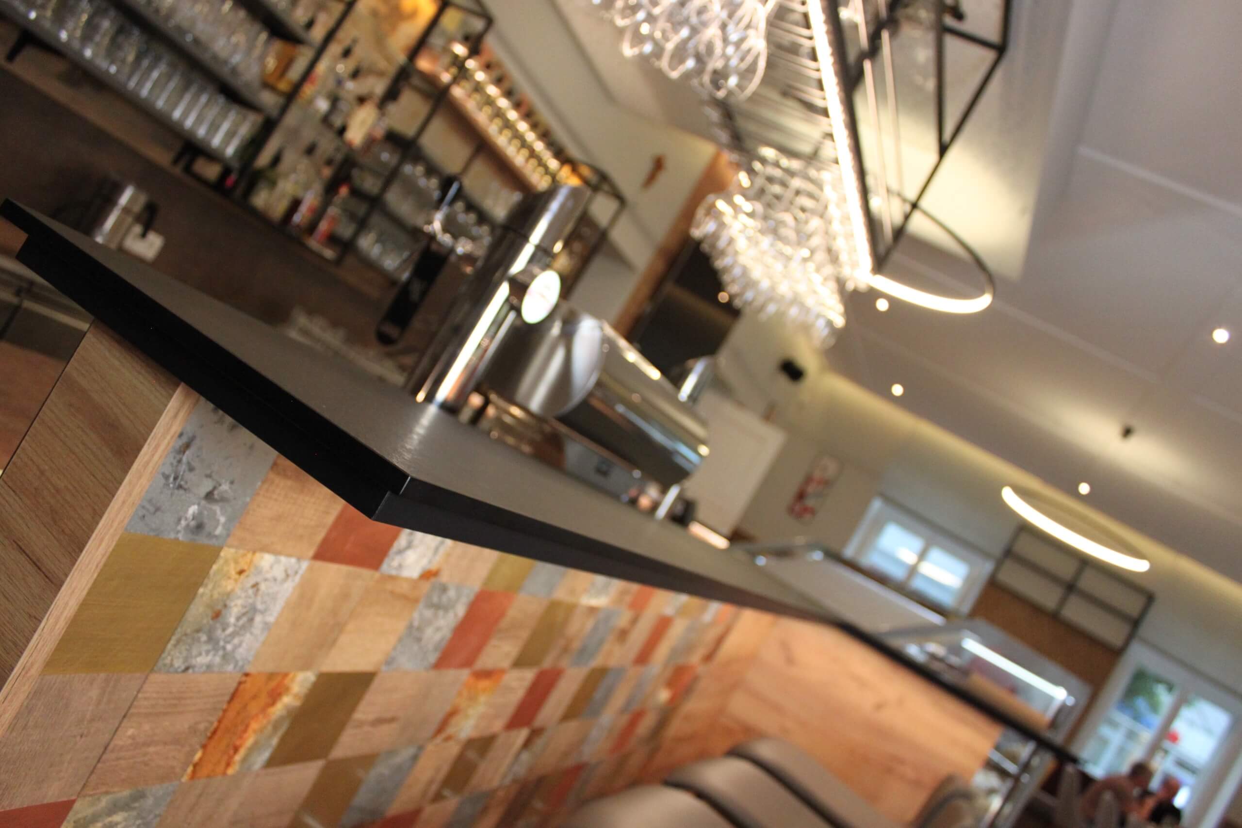 Moderne Bar mit stilvoller Beleuchtung und Holzdekor, Gläser hängen an der Decke.