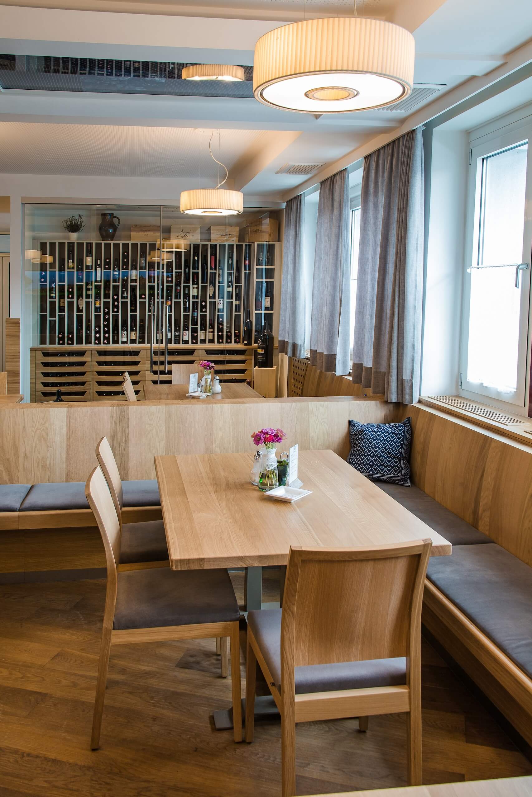 Moderner Restaurantbereich mit stilvoller Holzeinrichtung, Weinkühlschrank und gemütlicher Atmosphäre für Feiern.