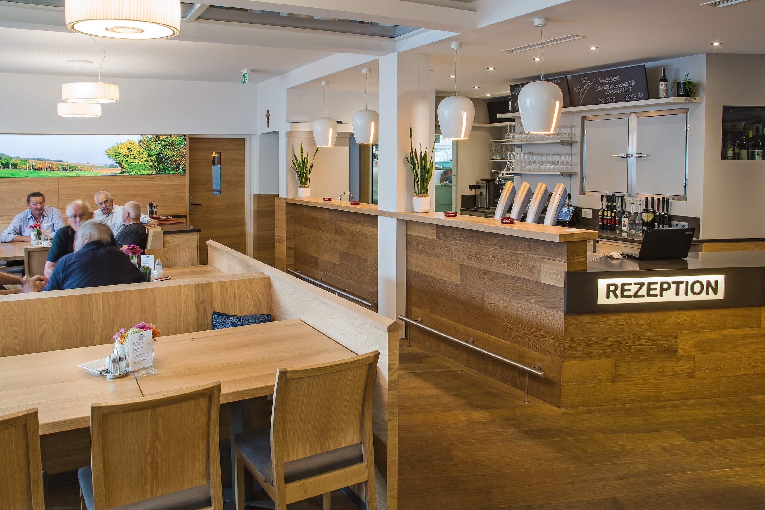 Moderne Rezeption und einladender Gastraum mit Holzmöbeln in hellem Café oder Restaurant.