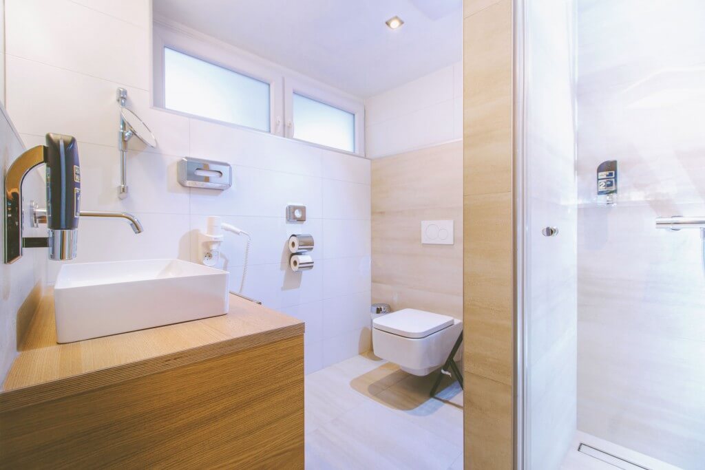 Modernes Badezimmer mit Waschbecken, WC und Dusche in heller, minimalistischer Einrichtung.