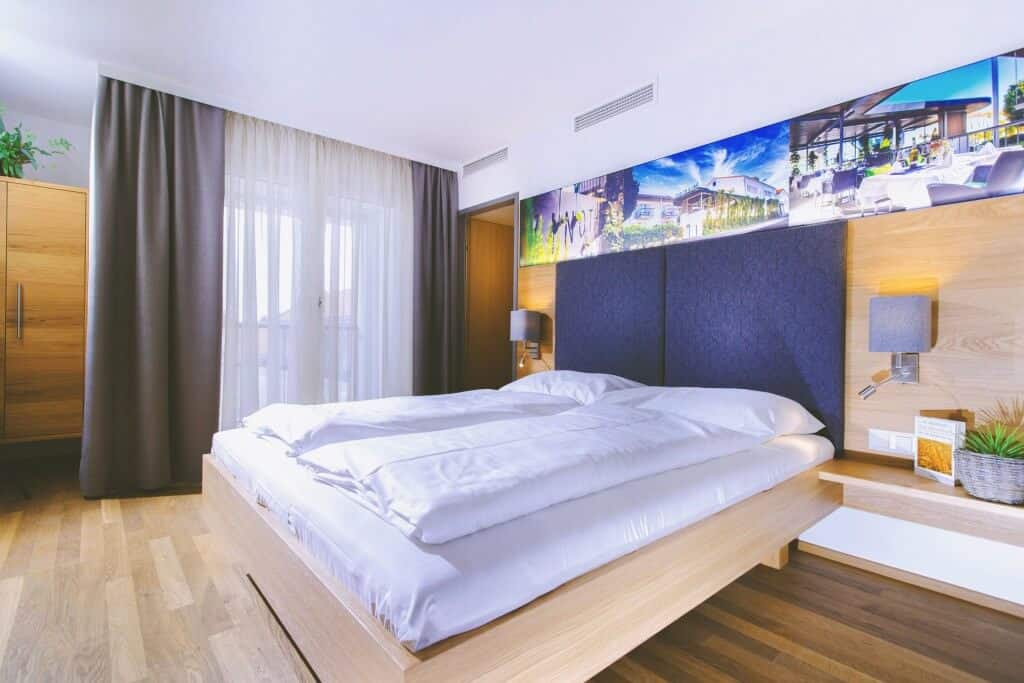 Modernes Hotelzimmer mit großem Bett, Holzboden und stilvoller Dekoration. Ideal für komfortable Übernachtungen.