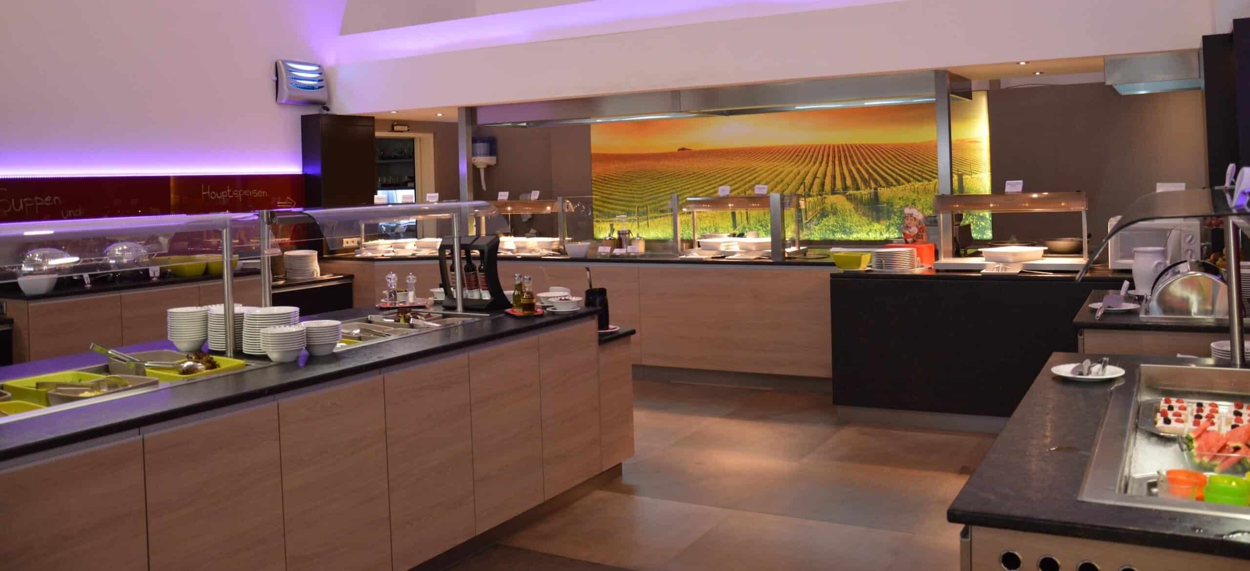 Modernes Buffetrestaurant mit beleuchteten Speisebereichen und Geschirr, ideal für Veranstaltungen und Caterings.