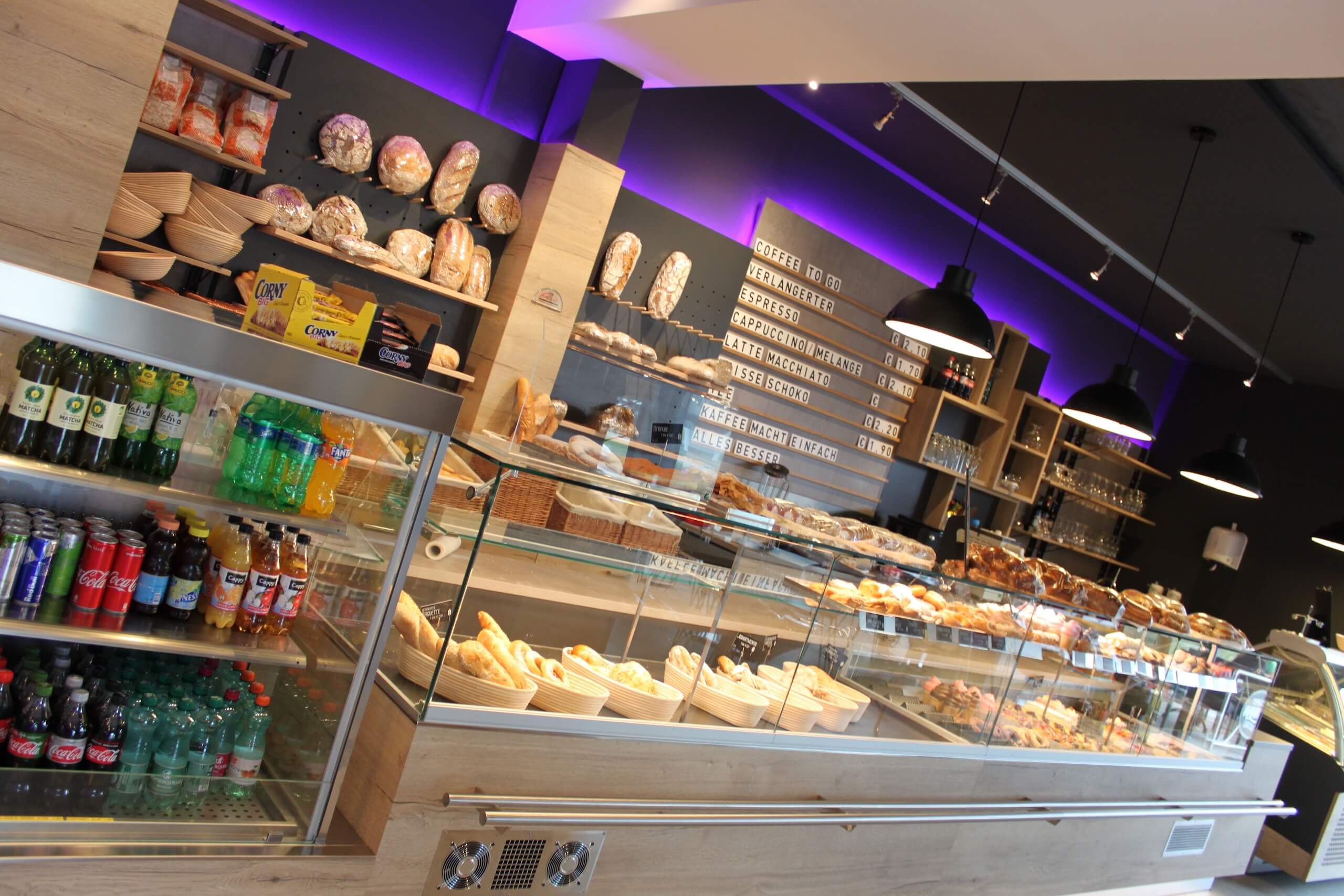 Moderner Bäckerei-Café-Verkaufsraum mit Brotauswahl, Snacks und Getränken. Einladende Atmosphäre für Kaffeeliebhaber.