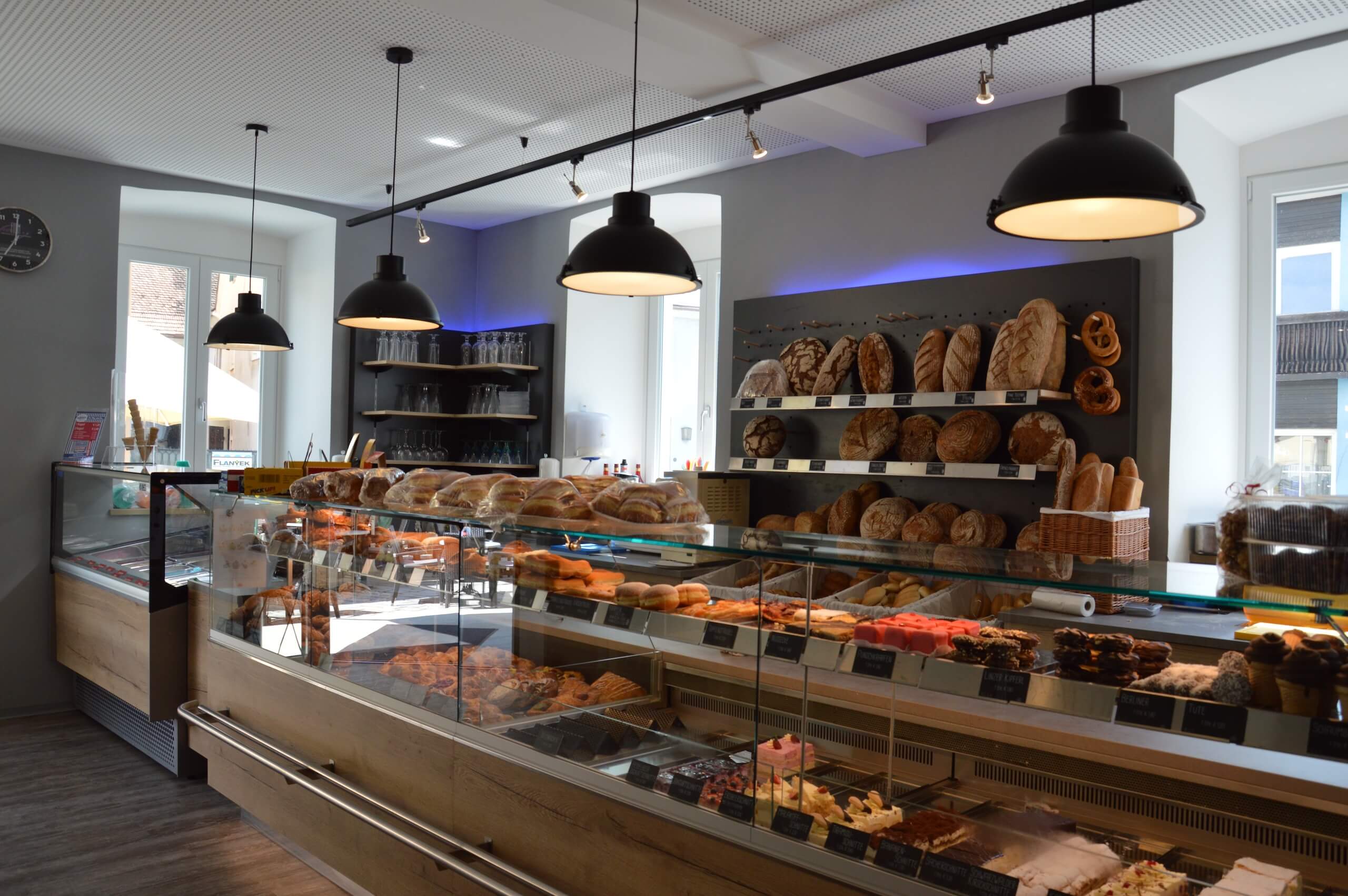 Moderne Bäckerei mit frischem Brot und Gebäck im Regal, hell beleuchtet und einladend gestaltet.
