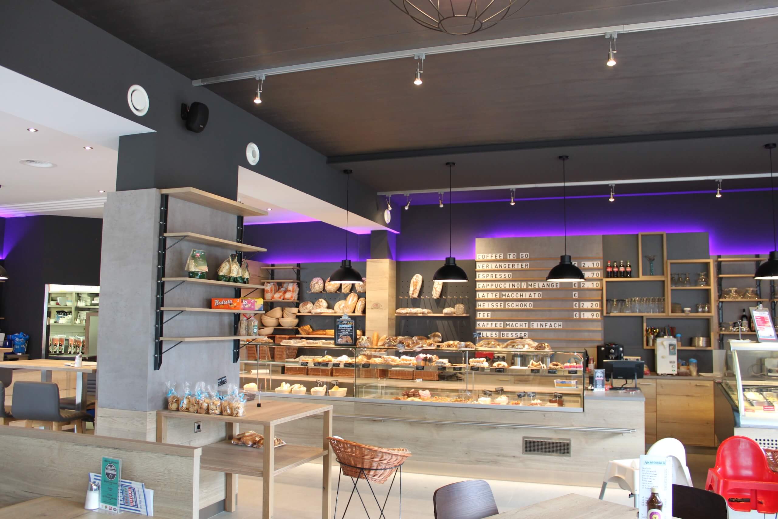 Moderne Bäckerei mit Verkaufsangeboten und Sitzmöglichkeiten, einladendes Design mit LED-Beleuchtung und Regalen.