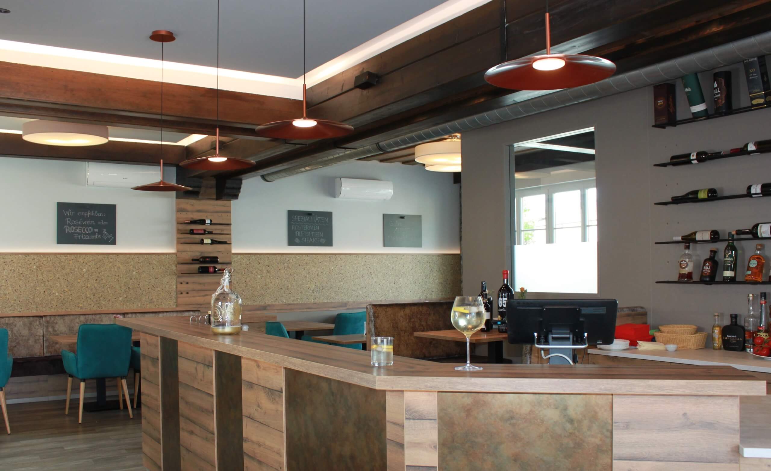Moderne Bar mit Holztresen, stilvoller Beleuchtung und Weinflaschen im Regal. Ideal für gemütliche Abende.