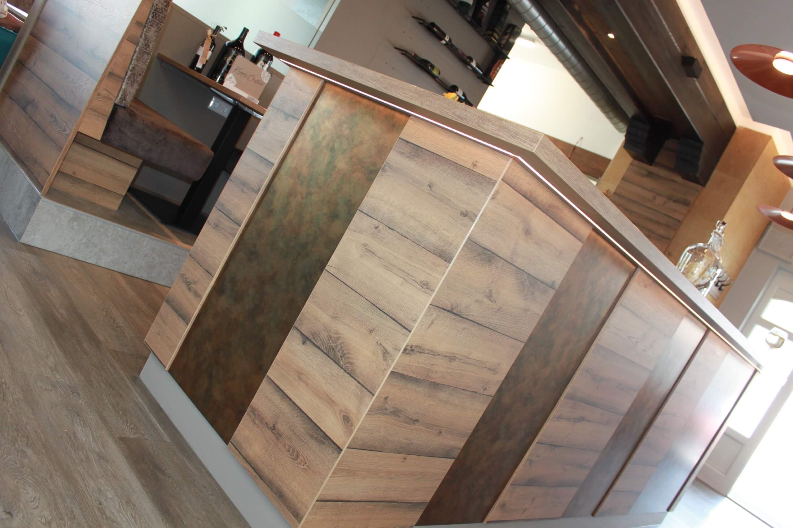 Moderne Bartheke mit Holzelementen und Flaschen im Hintergrund in stilvollem Restaurantinterieur.