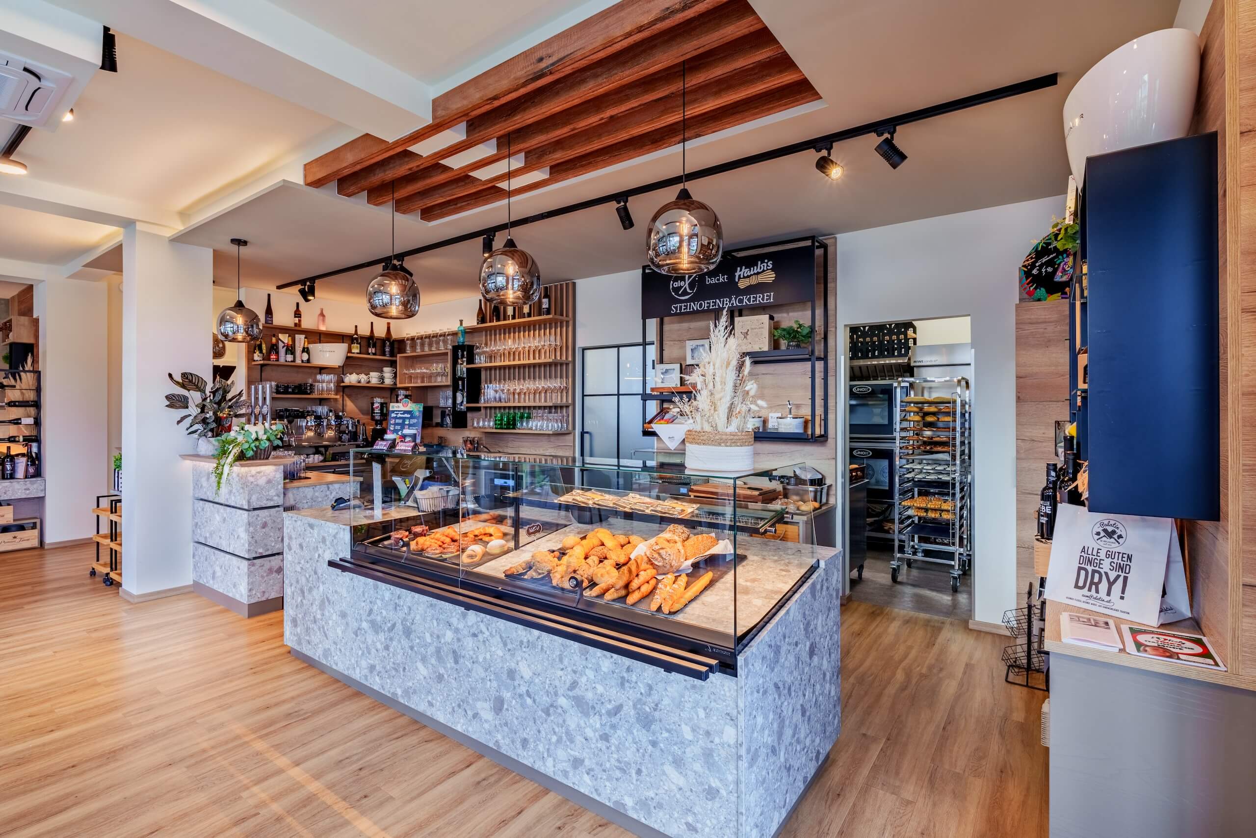 Moderne Bäckerei im Innenbereich mit frischem Gebäck auf Theke, hölzernem Dekor und stilvoller Beleuchtung.