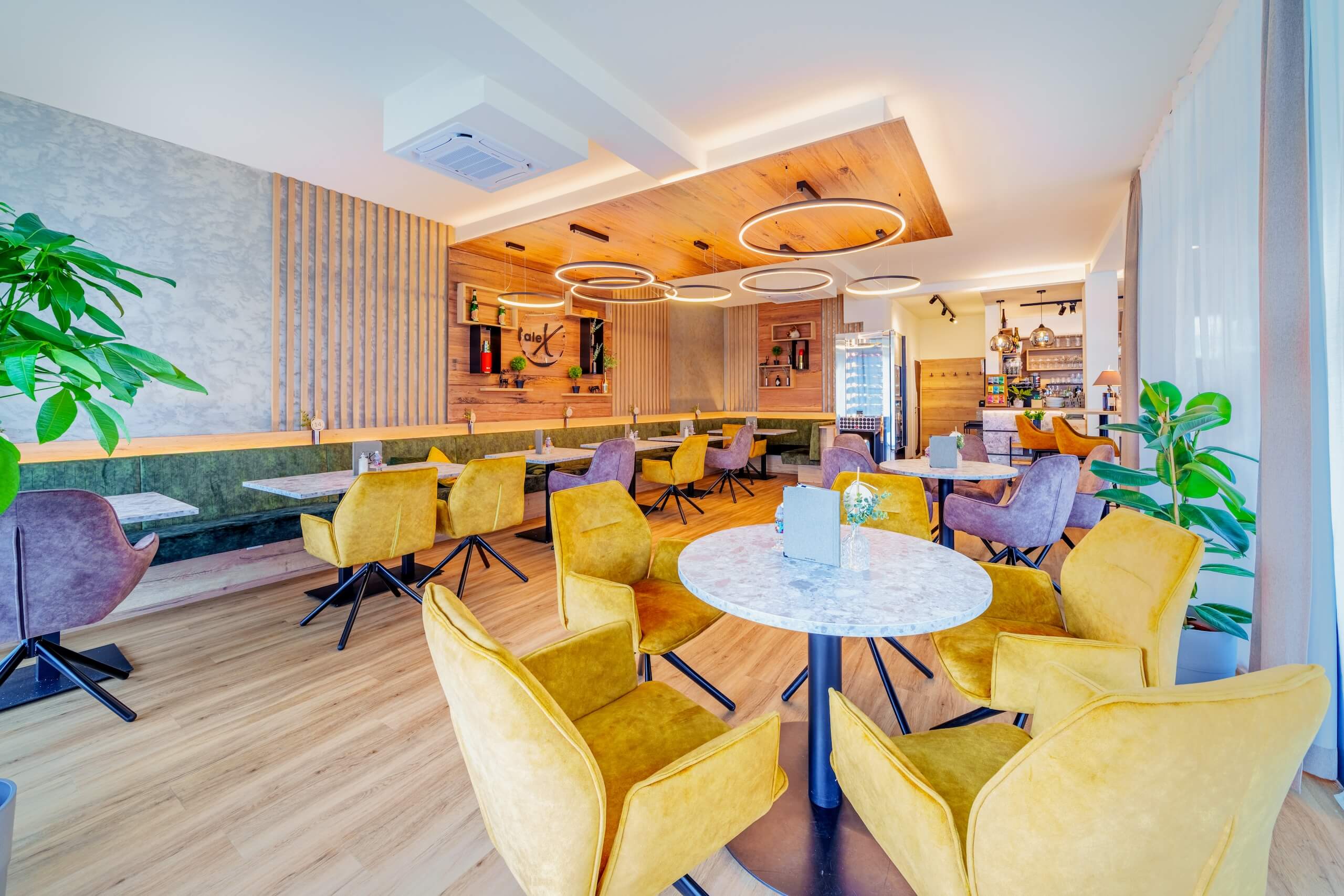 Moderner Café-Innenraum mit gelben und lilafarbenen Stühlen und stilvoller Beleuchtung, gemütliches Ambiente.