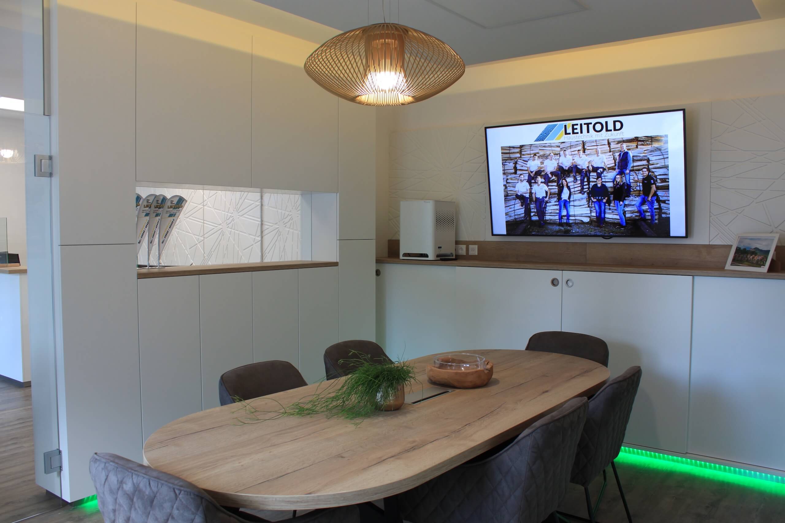Moderner Besprechungsraum mit Holztisch, Wandbildschirm und eleganter Beleuchtung für produktive Meetings.