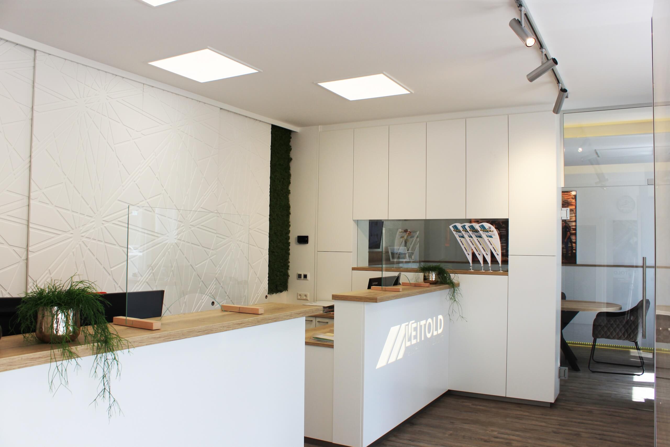 Moderne Empfangstheke mit Pflanzenakzenten und stilvoller Beleuchtung in Büro mit Glastrennwand.
