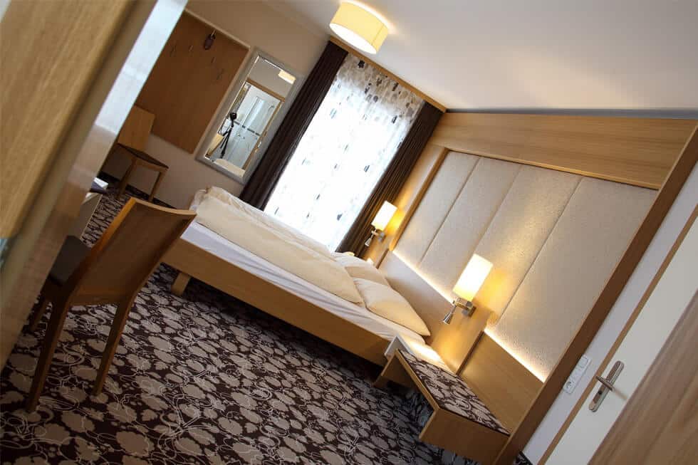 Moderne Hotelzimmer mit Doppelbett, stilvoller Beleuchtung und elegantem Teppich für erholsame Übernachtungen.