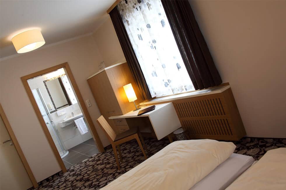 Helles Hotelzimmer mit Schreibtisch, weichem Teppich und eigenem Bad für komfortable Übernachtungen.