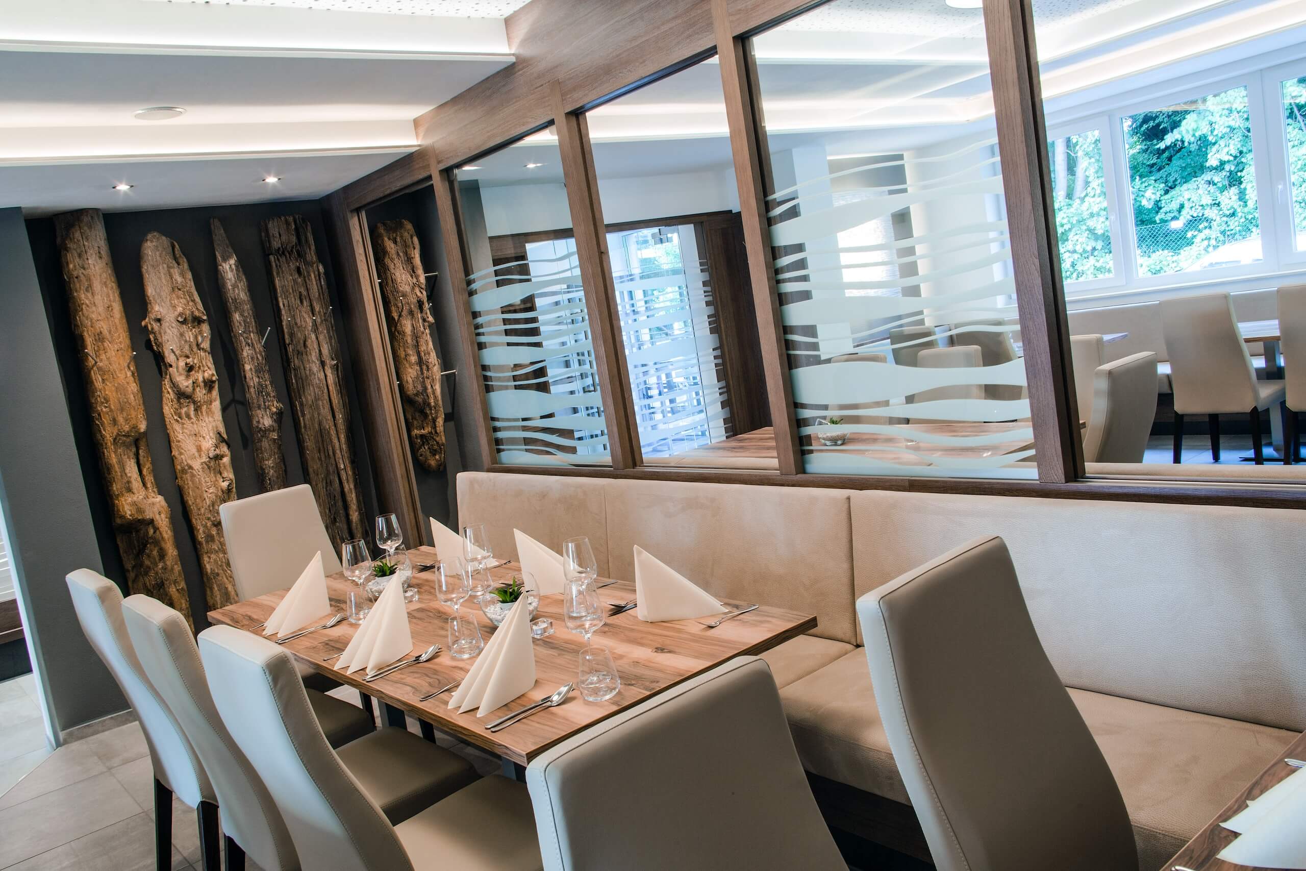 Elegantes Restaurantinterieur mit modernem Design, gedecktem Holztisch und stilvollen Stühlen in gemütlicher Atmosphäre.