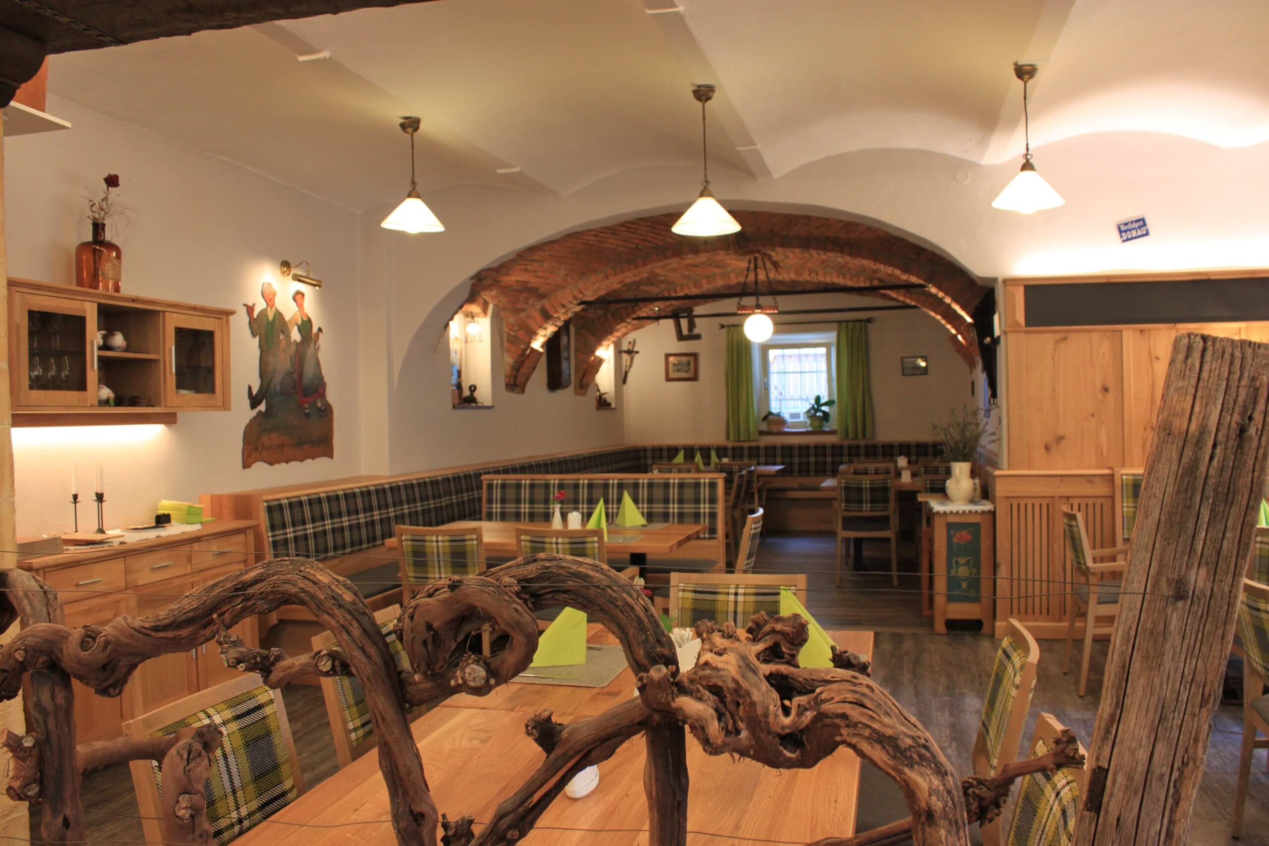 Gemütliches Restaurant mit rustikalem Holzinterieur und dekorativem Weinstock für eine einladende Atmosphäre.