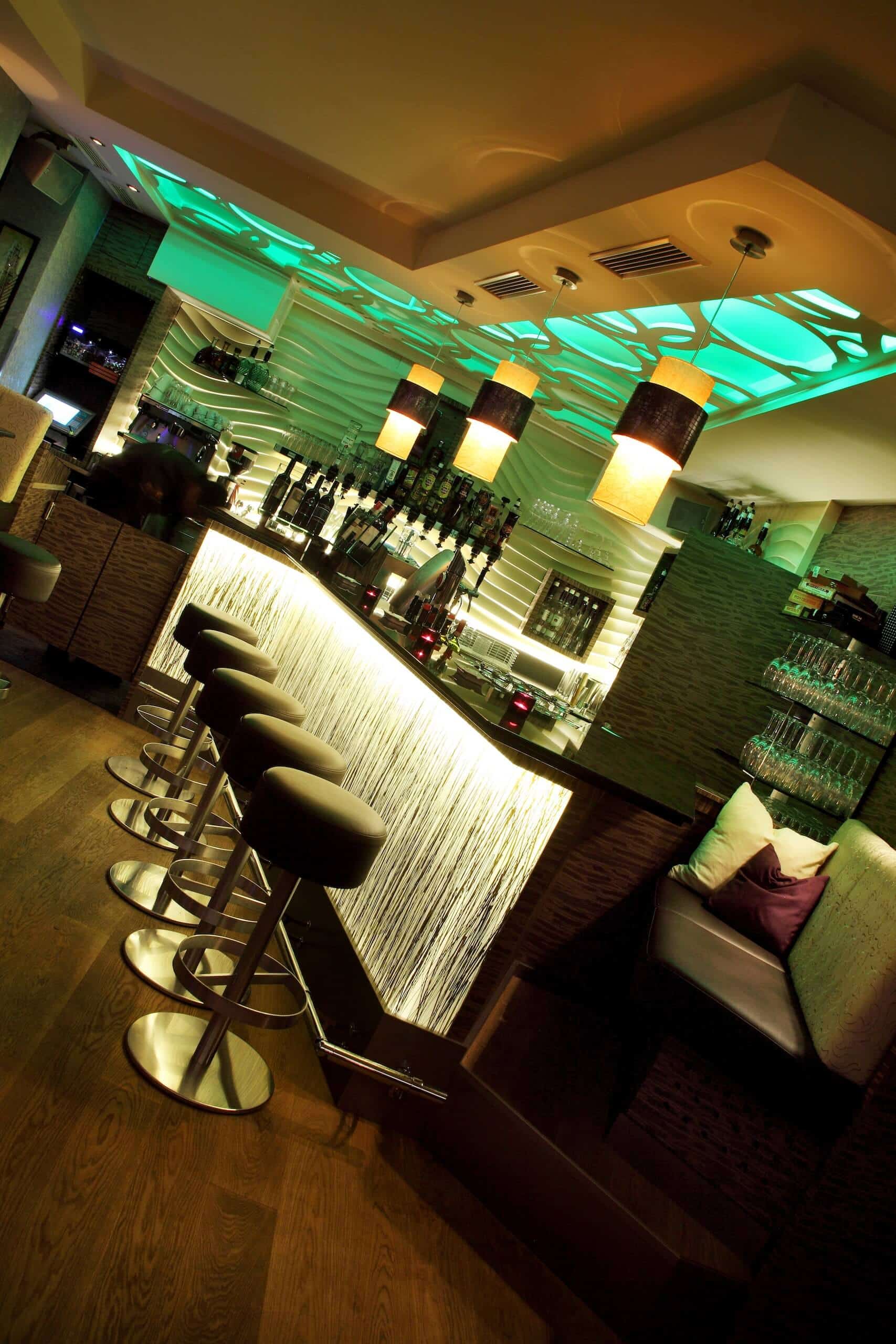 Moderne Bar mit stilvollen Hockern und stimmungsvoller Beleuchtung, perfekter Ort für Cocktails und Begegnungen.