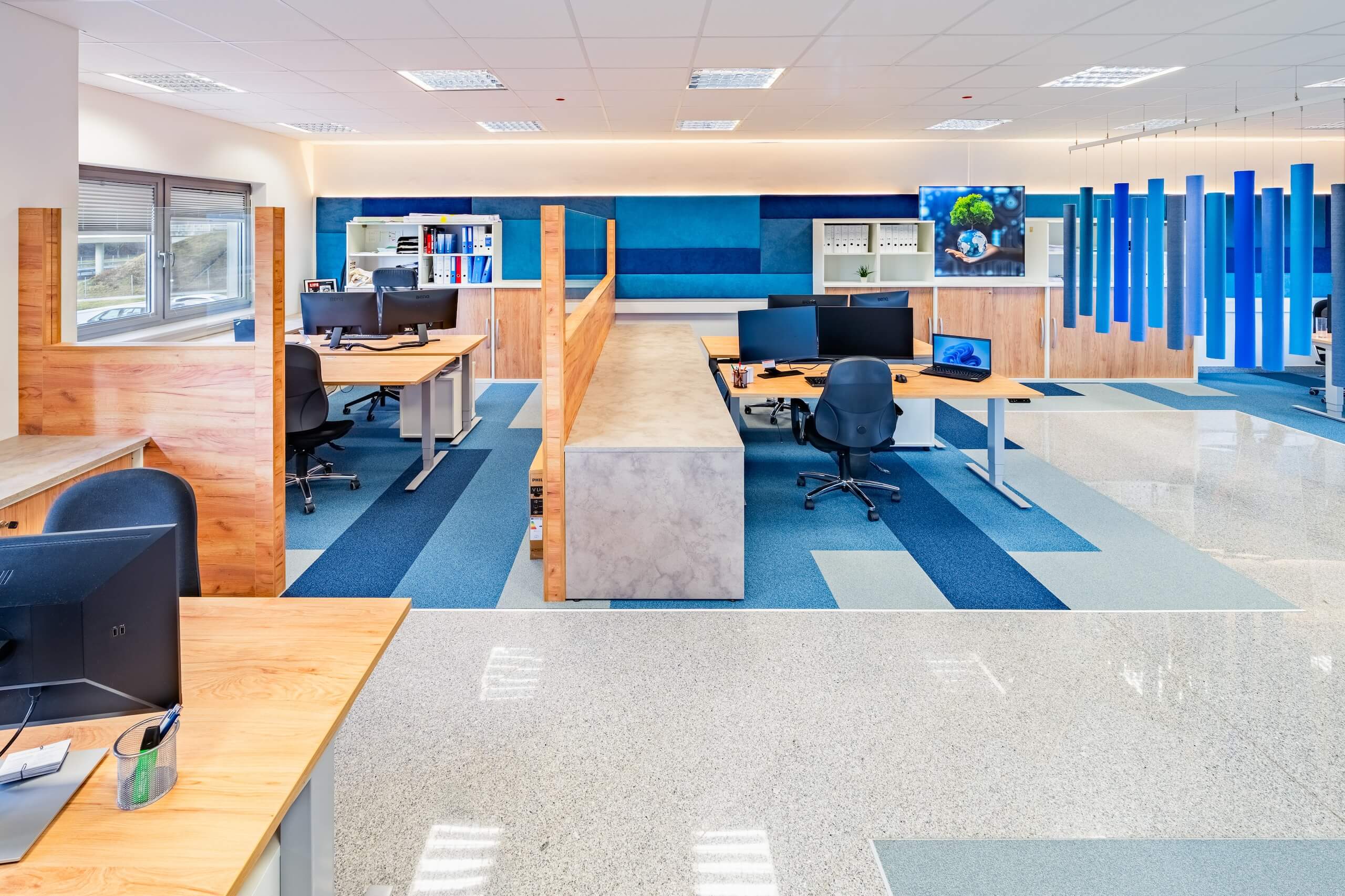 Modernes, offen gestaltetes Großraumbüro mit blauen Akzenten und ergonomischen Arbeitsplätzen für produktives Arbeiten.